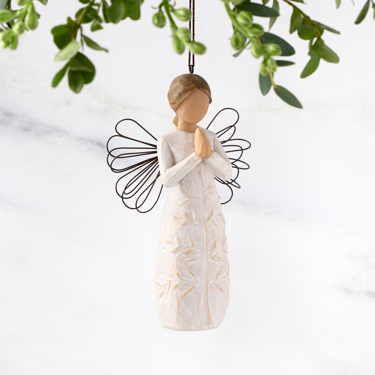 Female figure with wire wings in cream dress carved with a tree design, holding hands in prayer, ornament loop attached to head