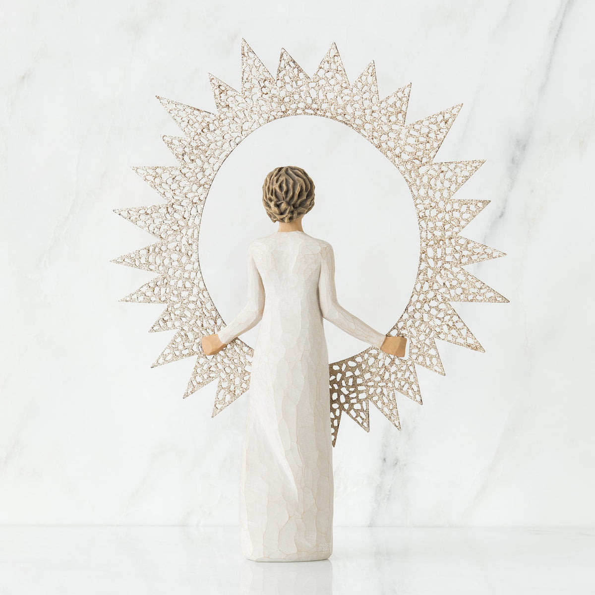 Back view of brunette girl figurine in white dress holding sun figurine up