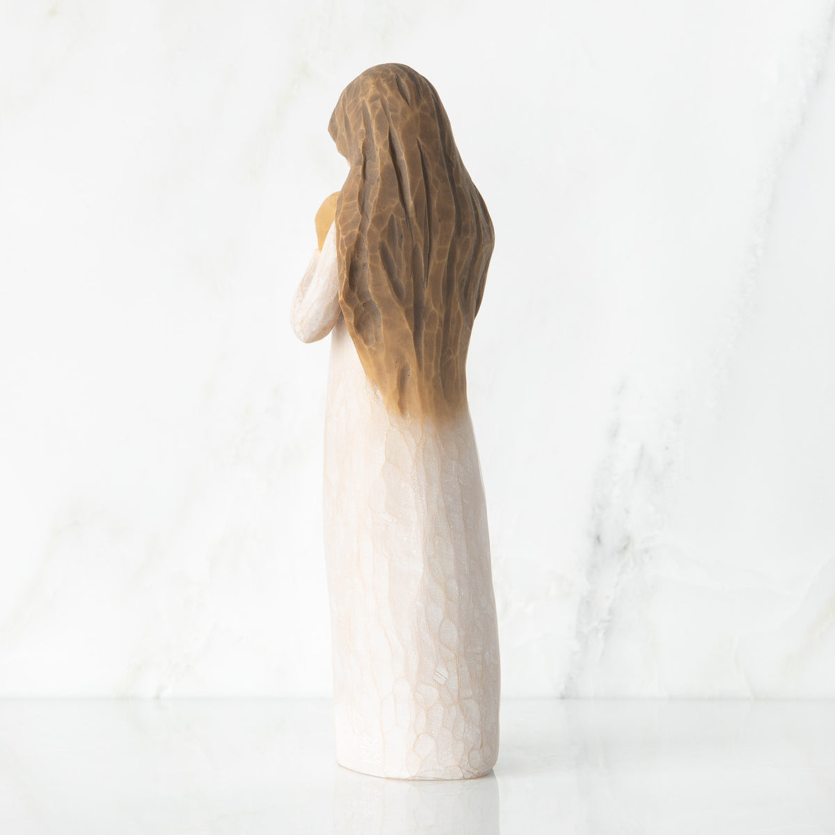 Back view, standing female figure in cream dress, hands surrounding small gold-leaf flame on chest