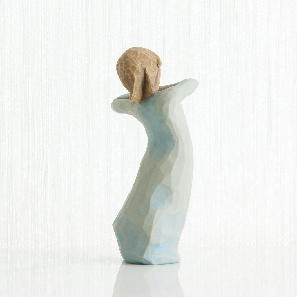 Back view of girl figurine in blue dress standing with her arms up