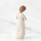 Back view of brown hair girl figurine standing in white dress