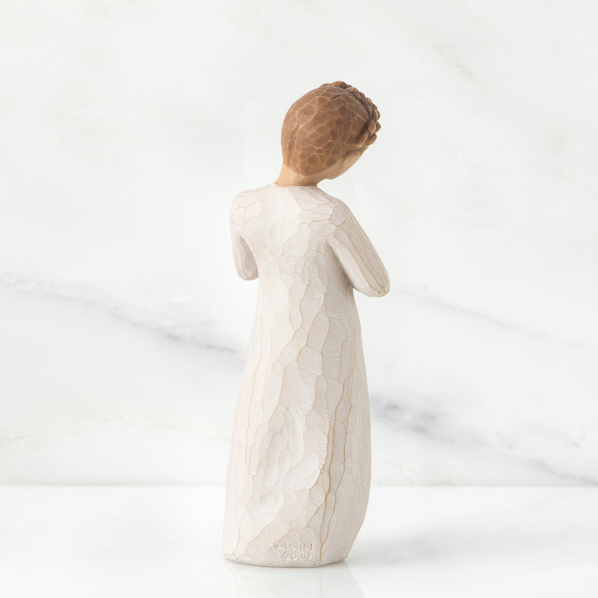 Back view of brown hair girl figurine standing in white dress