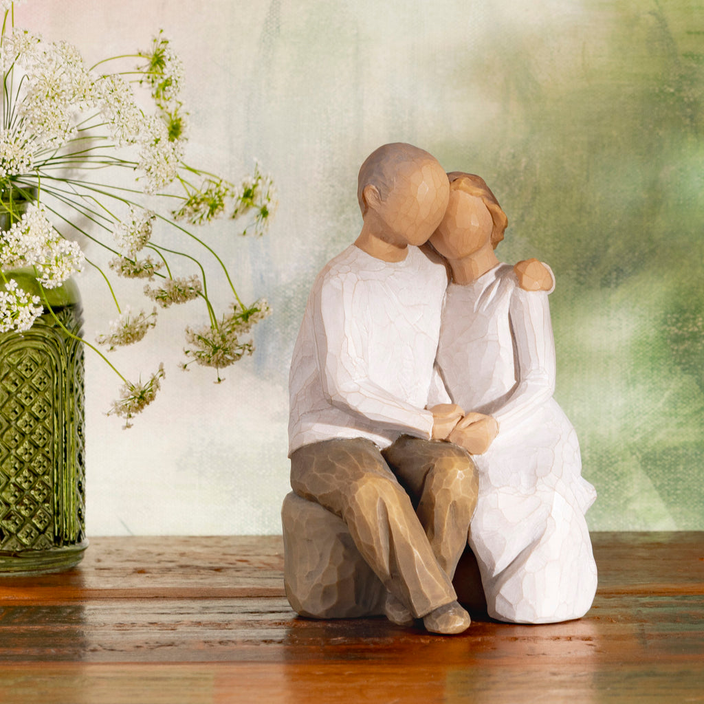Willow Tree Anniversary, 6”h hand-painted resin figure of older couple sitting on bench holding hands, both in neutral clothing, on wood shelf with wildflowers