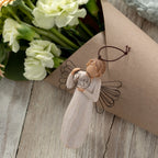 Willow Tree Just for You Ornament, 4”h hand-painted resin angel ornament in cream dress with wire wings, holding wire circle with 'thank you' written in wire, laying with floral bouquet