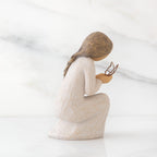 Right side view of kneeling female figure in cream dress, with wire butterfly on extended hands