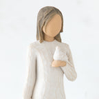 Close view of brunette girl figurine in white dress holding white dove