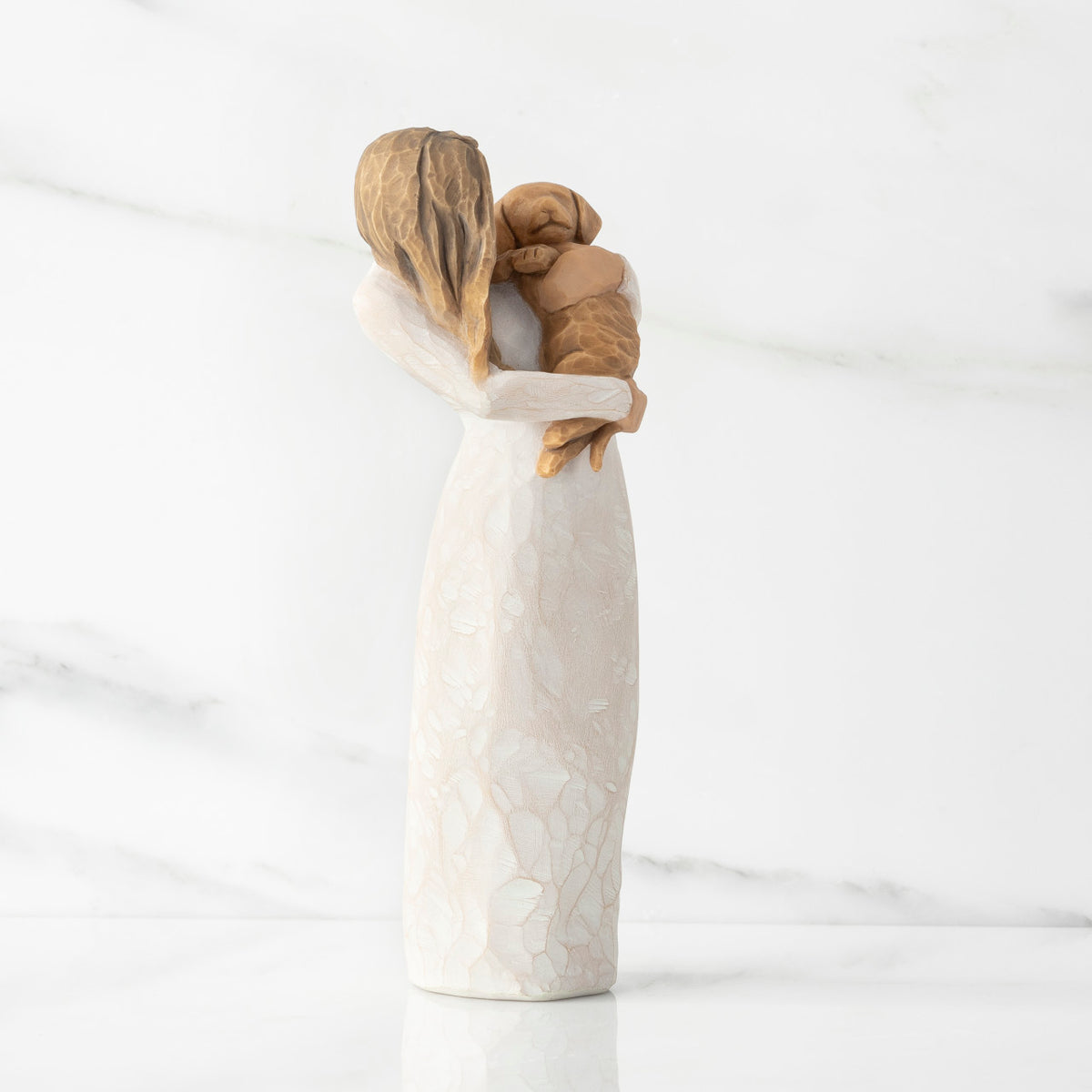 Right view, standing female figure in cream dress, holding golden color puppy in her arms