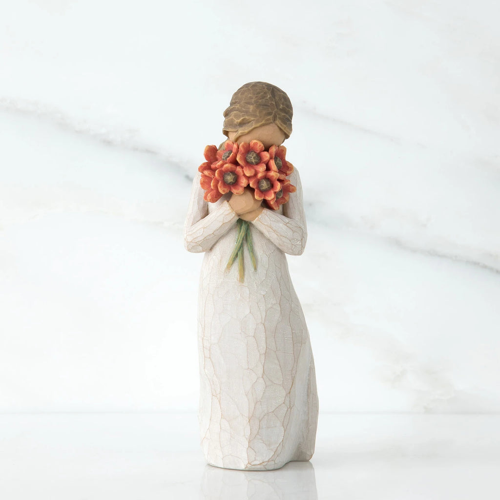 Small girl figurine wearing white dress holding red flower boquet in her hands