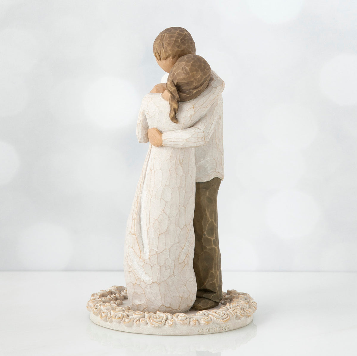 Man and woman figurine hugging one another on round cream plaque