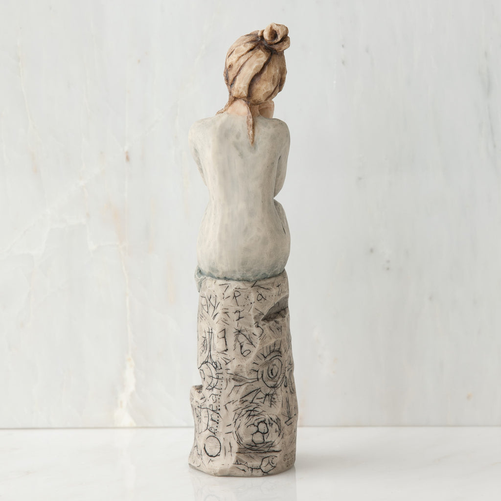 Back view of brunette girl sitting on grey rock