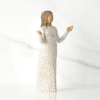 Side view of brunette woman figurine in white dress with gold dots holding her hands up
