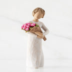 Right side of standing figure in cream dress holding bouquet of pink tulips