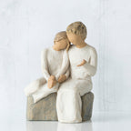 Two faceless figurines wearing white sitting next to each other on rock