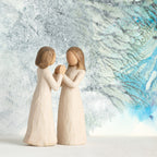 Willow Tree Sisters by Heart, two separate 4.5”h hand-painted standing resin figures in cream dresses with hands that fit together, in front of blue and celadon painting