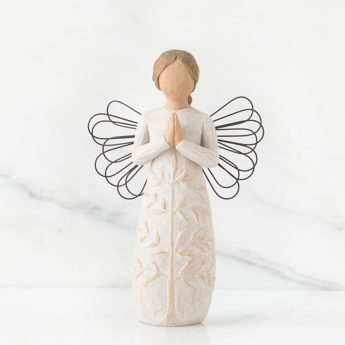 Faceless woman figurine in white dress with black wire angel wings - her hands are folded in prayer form