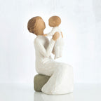 Mother figurine holding baby in her lap - both faceless, wearing white