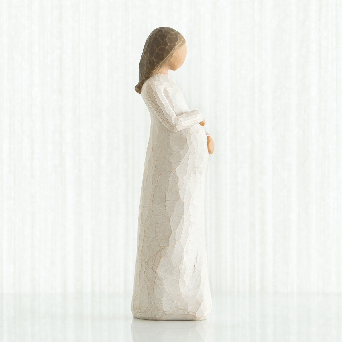 Side view of brunette girl figurine in white dress holding her stomach