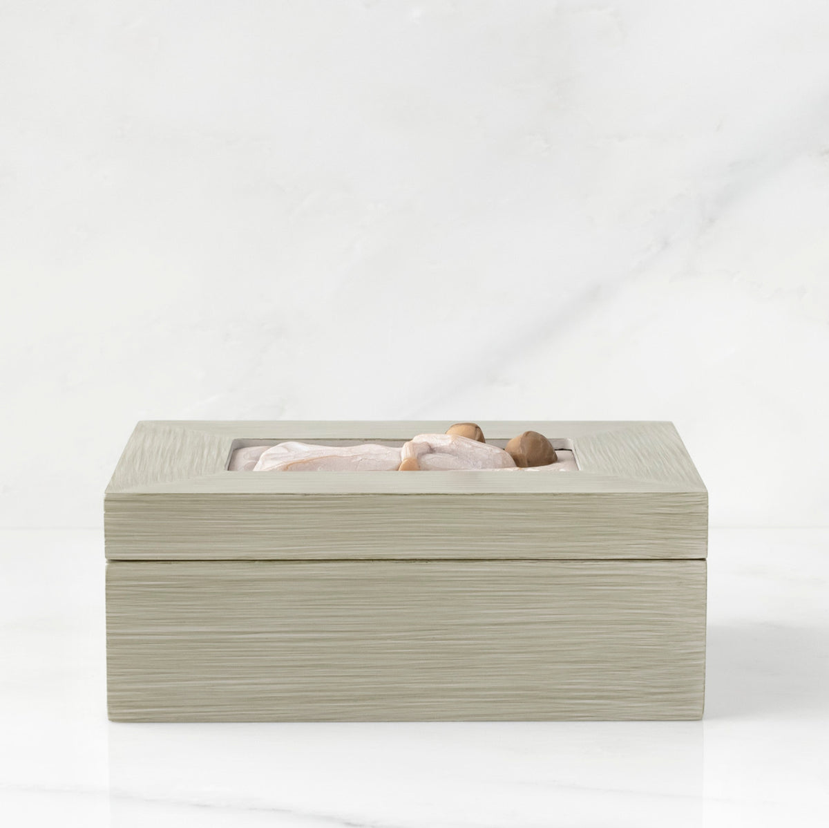 Side view: Light gray rectangular wood box with hinged lid, carving on lid of female and child embracing in cream dresses