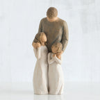 Man faceless figurine wearing brown shirt standing over two faceless girl figurines in white dresses