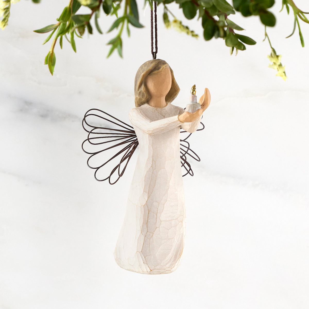 Figure with short brown hair wearing cream dress holding out a candle in her hands, ornament hook attached to head