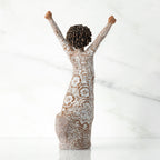 Right back of figure, with arms raised overhead, dress etched with African textile patterns