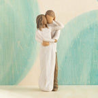 Front view of couple, standing with arms around each other. Woman has darker skin and hair; man has lighter skin and hair. Blue painted background.
