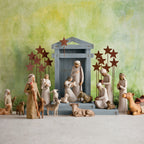 Far front view of grey barn with wiseman figurines, golden cows, and white sheep figurines around the barn - green background