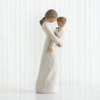 Side view of faceless mom figurine wearing white dress holding child in white outfit in her arms