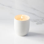 Lit filled scented candle with unglazed cream tapered cylinder vessel, sentiment written in gold inside rim, plant-based wax blend, all-cotton wick