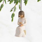 Front view: Ornament of seated figure reading a book; 2026 in raised gold numbers on rock; loop and hook in head