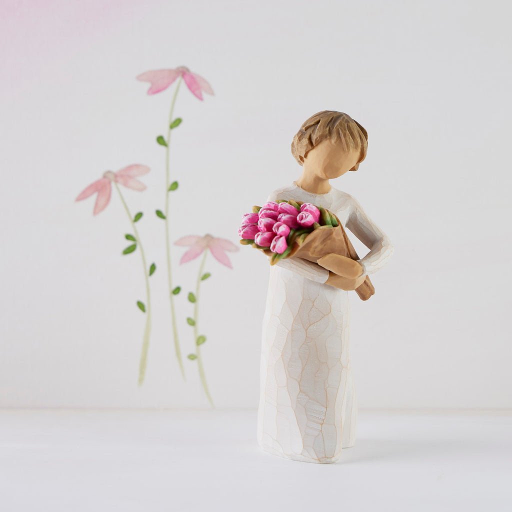 Willow Tree Bright Hope, 4”h hand-painted standing figure in cream dress, holding bouquet of bright pink tulips, in front of white painting