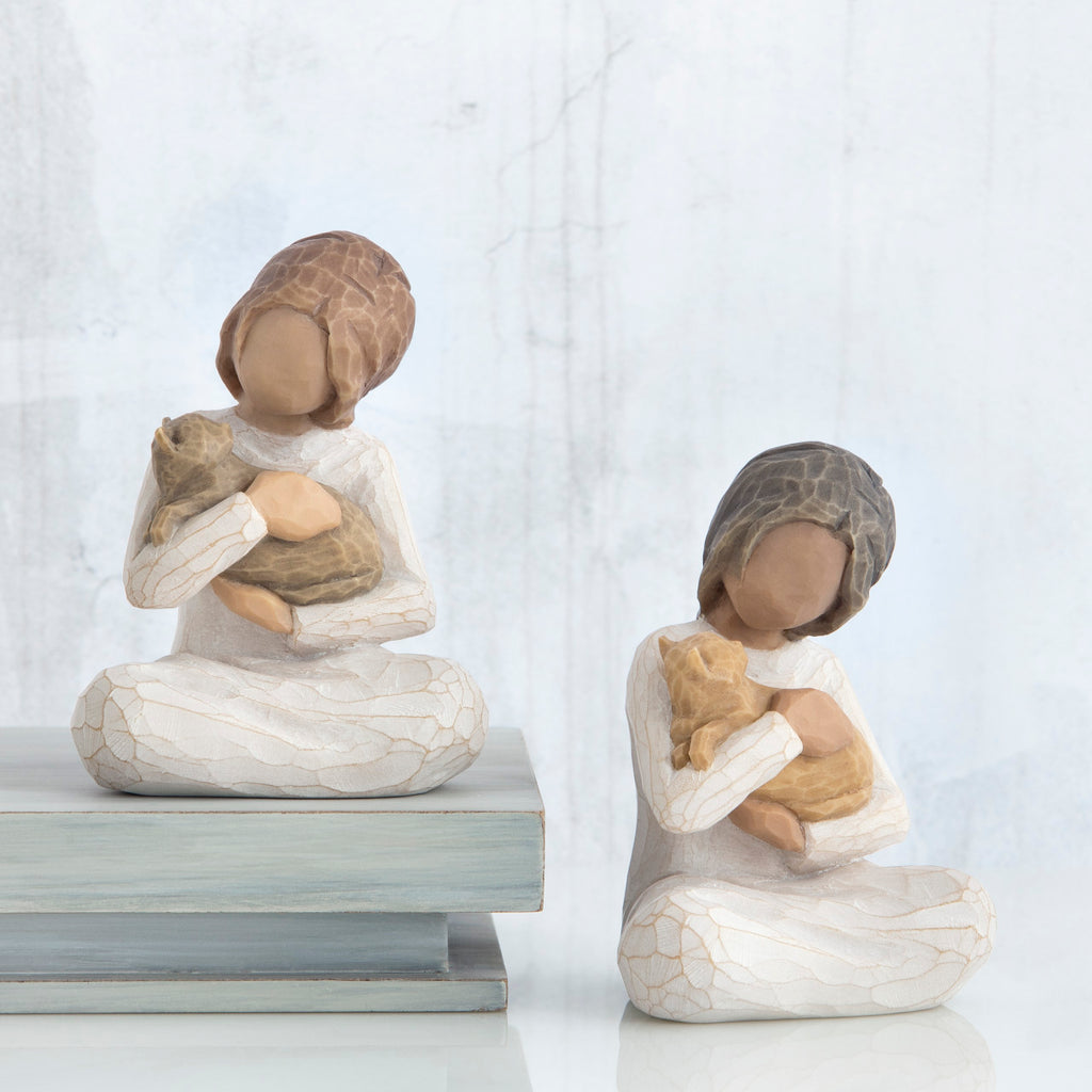Set of two brunette girl figurines sitting down holding golden cats - all white background