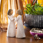 Willow Tree Sisters by Heart, two separate 4.5”h hand-painted standing resin figures in cream dresses with hands that fit together, on dresser with jewelry and succulent