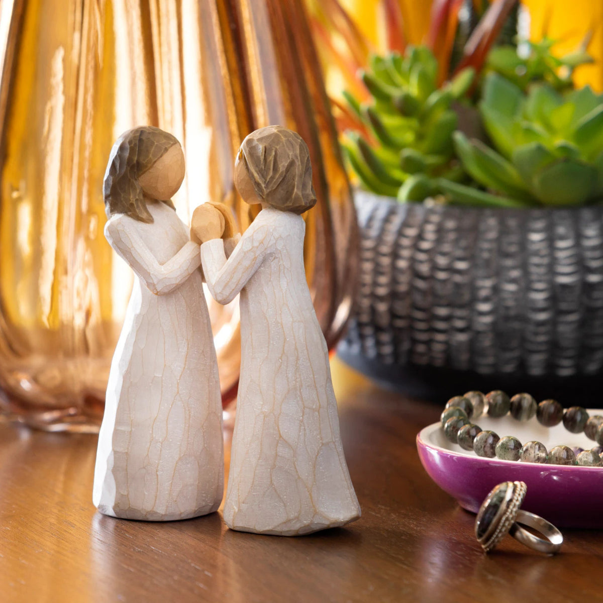 Willow Tree Sisters by Heart, two separate 4.5”h hand-painted standing resin figures in cream dresses with hands that fit together, on dresser with jewelry and succulent