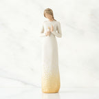 Brunette girl figurine in white dress holding white candle in one hand