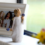 Willow Tree Lavender Grace, 5.5”h hand-painted standing resin figure in cream dress, holding two bundles of lavender flowers - one in raised hand, one at her side, on windowsill