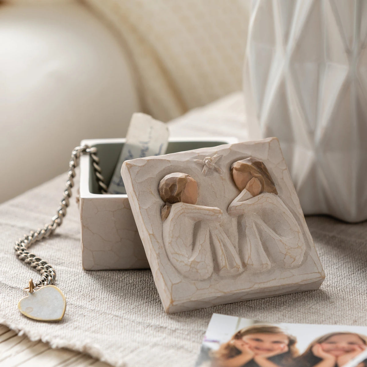 Willow Tree Friendship Keepsake Box, 3”sq x 2”h hand-painted resin box with removable lid off to one side, jewelry inside box. Lid has bas-relief carving of two seated figures in cream dresses, facing each other, inside of box has sentiment