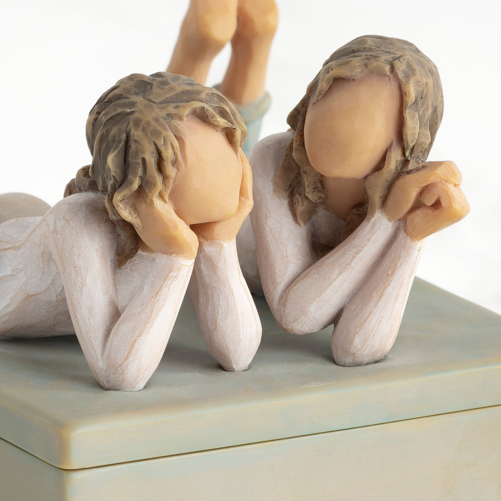 Front view of closed rectangular blue-gray resin box, detail of two girls’ faces, turned to show height of box sides