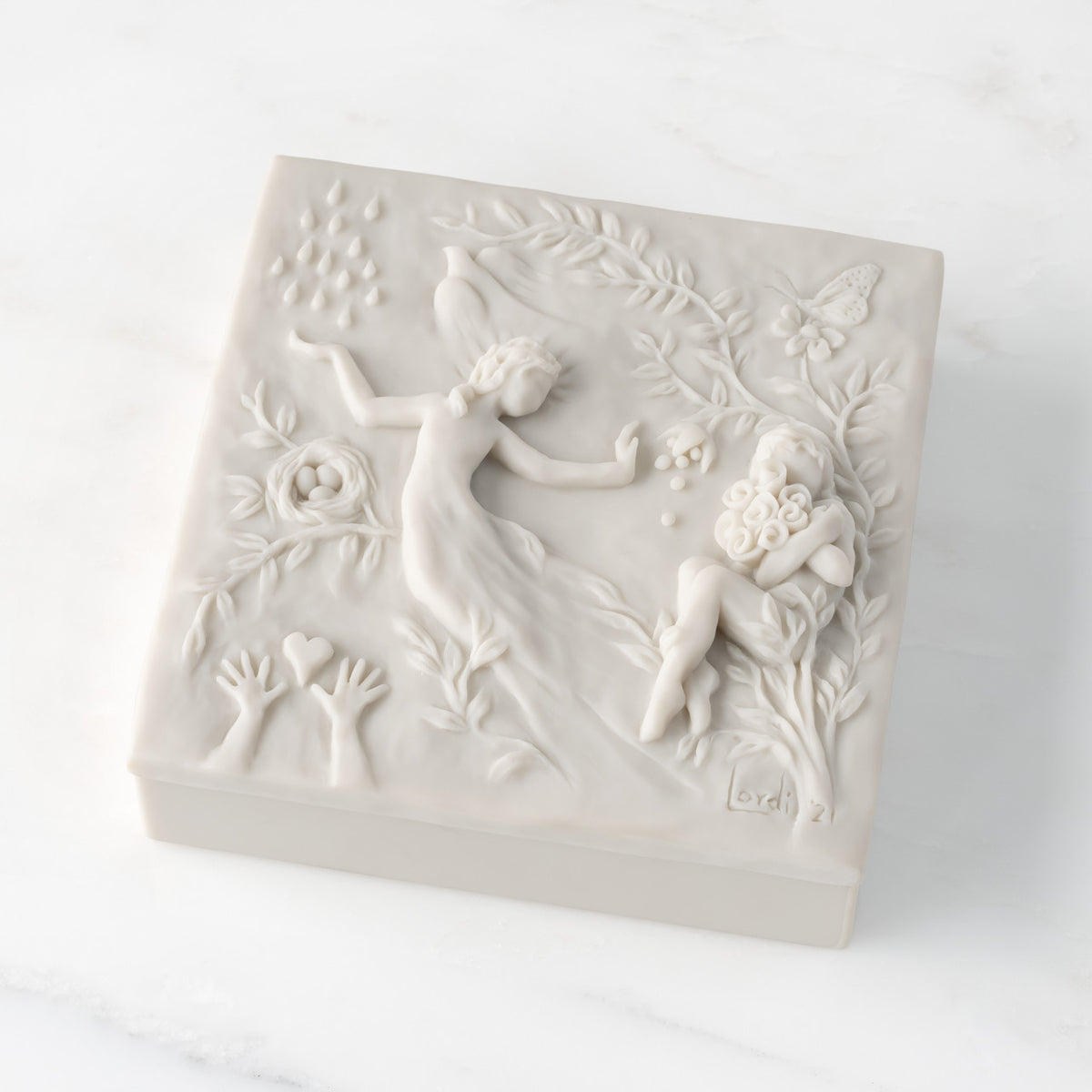 Closed white resin square box; lid carved with figural and organic imagery