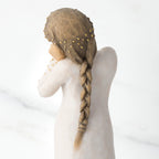 Cropped view of back of figure, showing braid with gold lead dot detail in hair