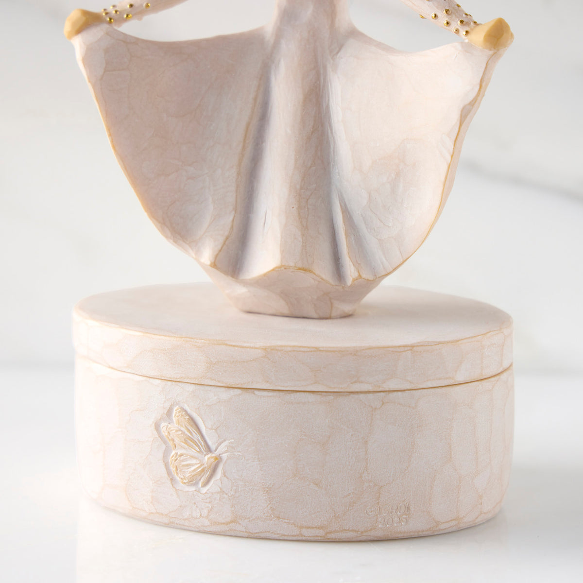 Detail view: back of oval resin box, showing carved butterfly detail on box base