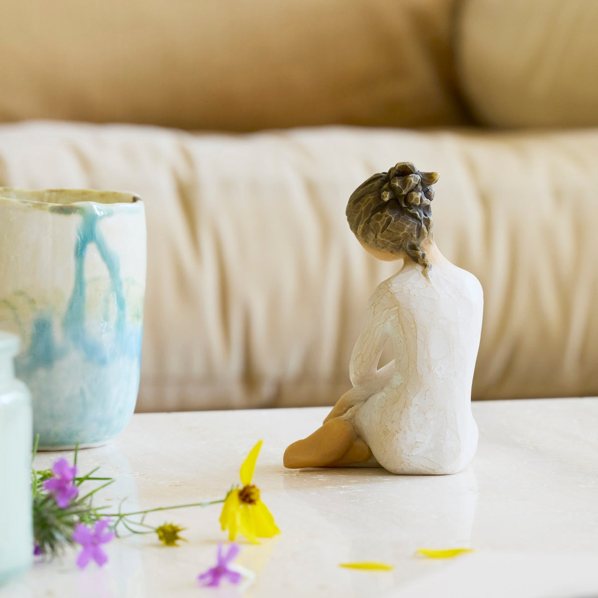 Willow Tree Serenity, back view of 3.5”h hand-painted seated figure in cream dress, arms crossed in balletic pose, on bedside table