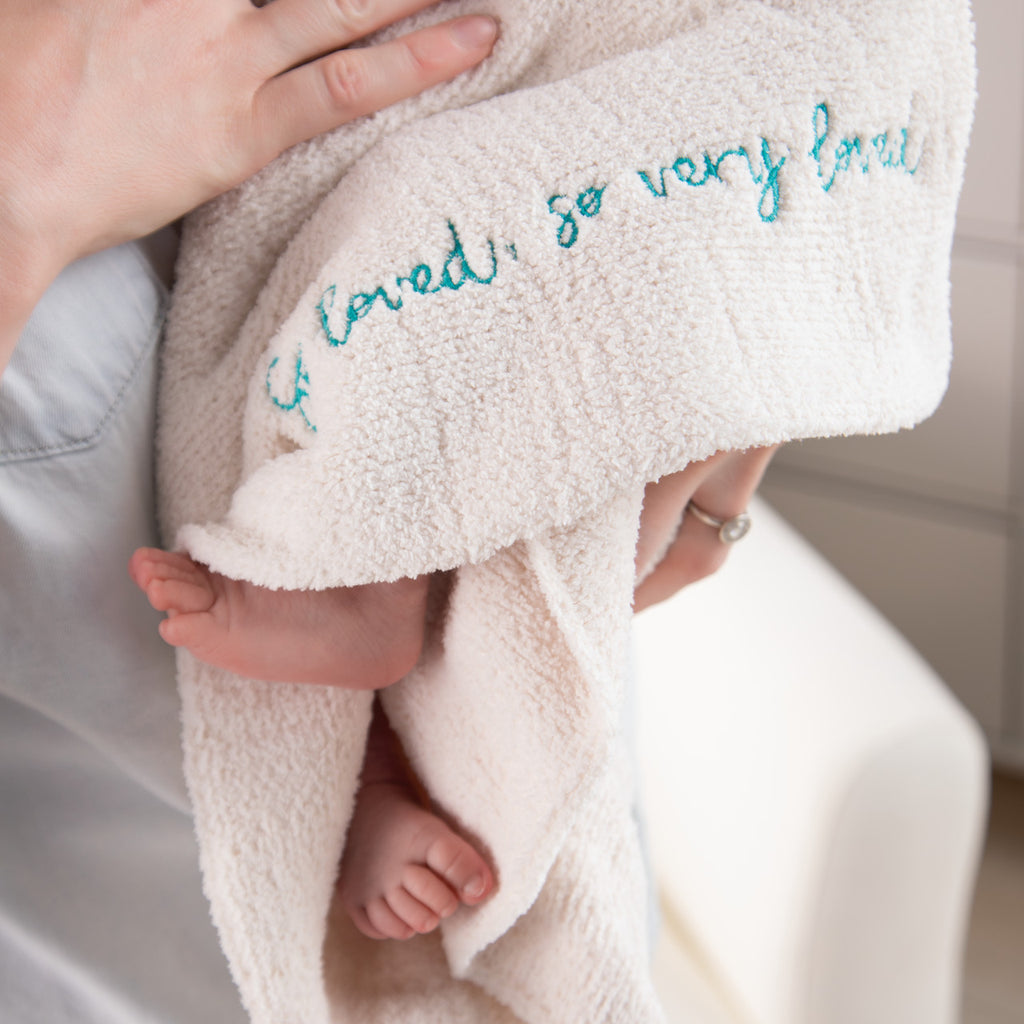 Close view of cream towel that says 'so loved, so very loved' in blue