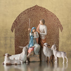 Mary and joesph figurines holding baby with four sheep figurines around them - brown sheer barn paper behind them