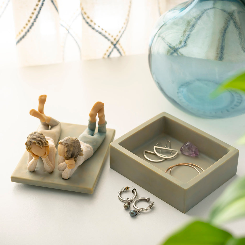 Willow Tree Forever Friends Keepsake Box, 4.25”d x 3.5”w x 3.75”h hand-painted blue-gray rectangular resin box, sculpture of two girls lying next to each other affixed to lid, open with jewelry inside